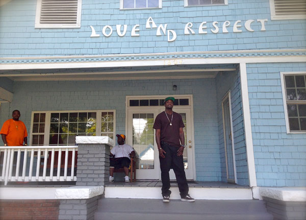 Willie Johnston stands on the steps of Love and Respect with a smile on his face, as Dennis Garrett, owner and founder, on the far left hand side looks on.  Another resident of the house sits, and listens to his music. (Staff photo by Sheila Rosier)  