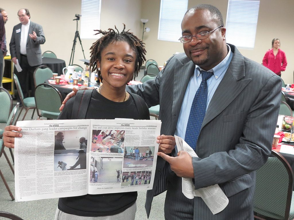 YO: Durham intern Nautica Lane grins as she sees her story-photo spread for the first time in the Durham VOICE, as Teen Mentoring Coordinator Carlton Koonce looks on proudly. (Staff photo by Jock Lauterer)