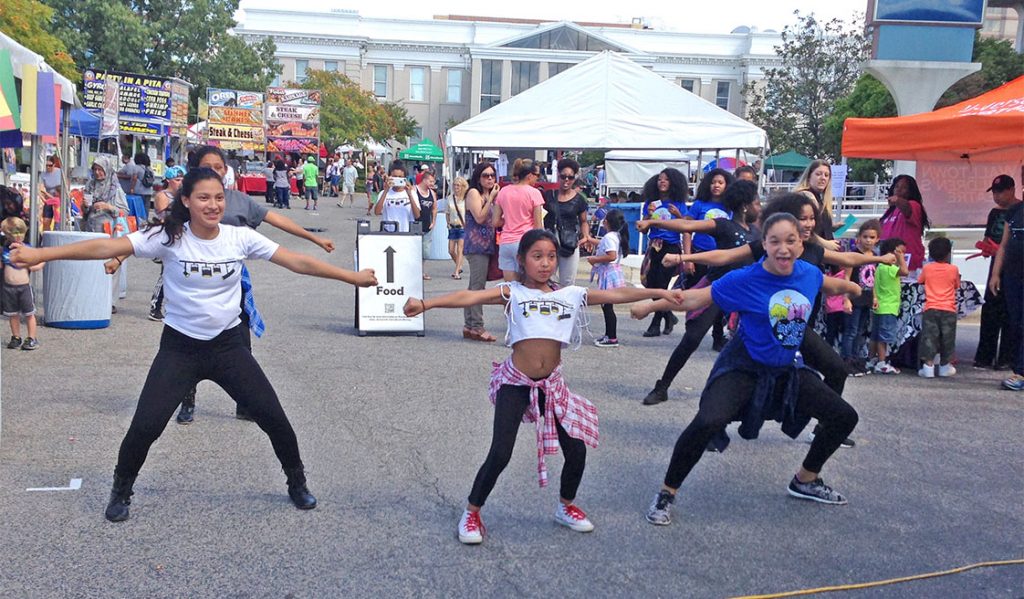 The students in the senior dance company move gracefully to Bollywood music in front of their non-profit tent for a large crowd at the CenterFest. At the end of the performance spectators cheered and applauded the lively group of young dancers. (Staff photo by Brittney Bizzell)