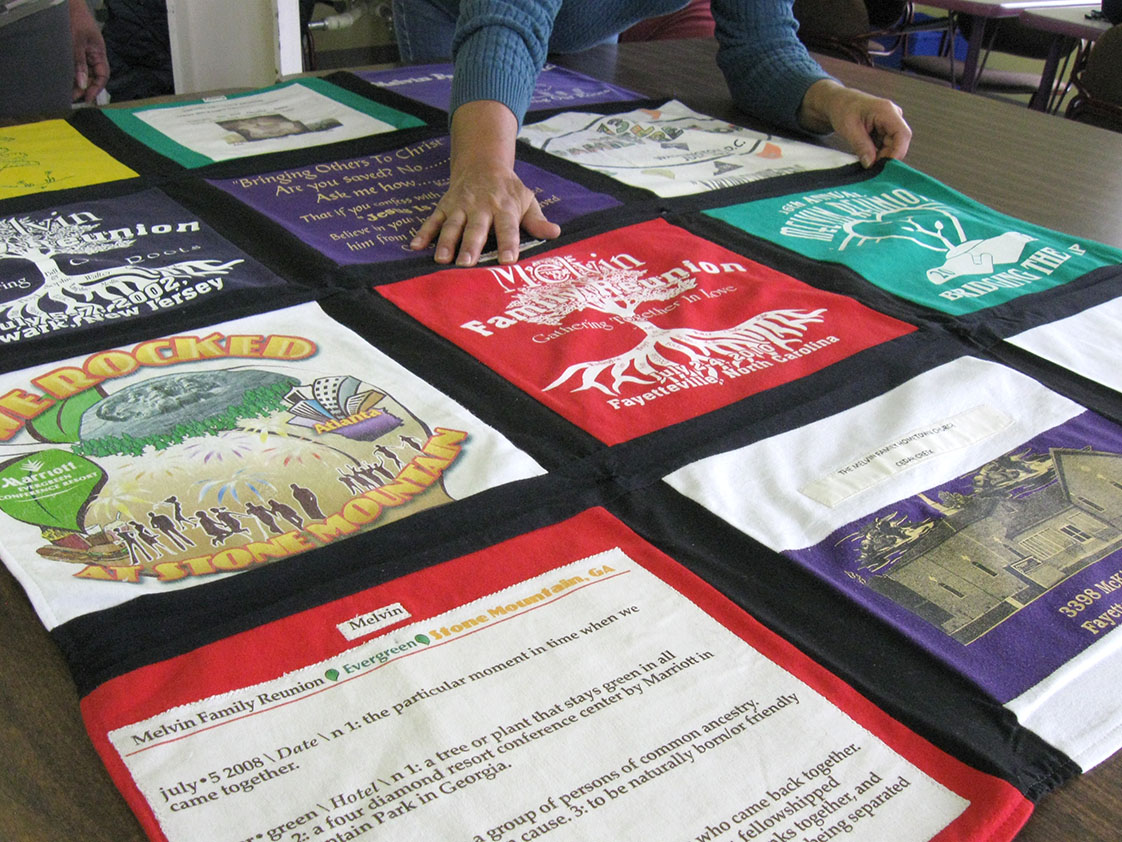 Robinson joined the quilting group over the summer of 2015, and is showing Farmer her most recently finished piece. It is a quilt of all her past family reunion t-shirts that she is going to take and hang up at her upcoming family reunion. (Staff photo by Candice Craig)