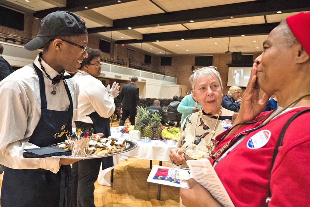 Some of the people at the event weren’t expecting to be catered the wide variety of food. “Mmm, these vegetables are good! I’m not leaving this table!” says the lady on the right while laughing with student Khariya Moore (left). (Staff photo by Cole McCauley)
