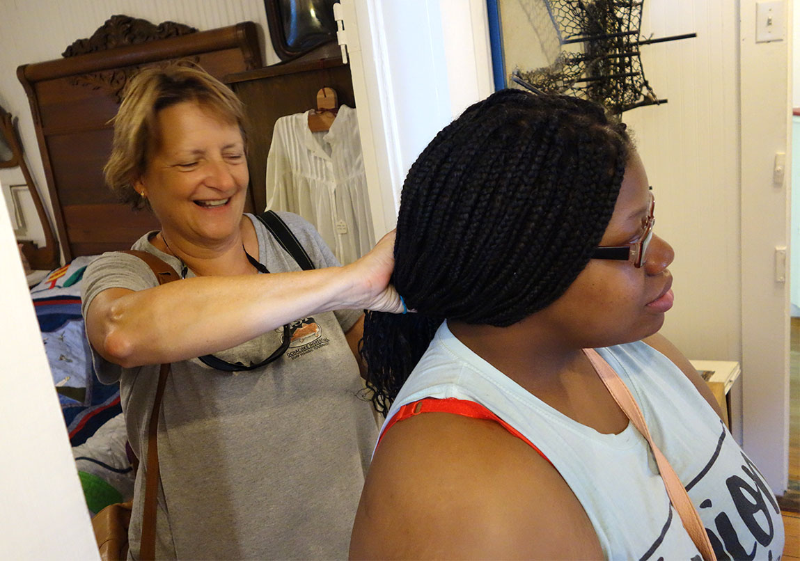 Getting to know you: Ocracoke Observer co-owner Connie Leinbach lends a hand, tying back PYO intern Christian Lawrence's braids during a tour of historic Ocracoke. (Jock Lauterer photo)