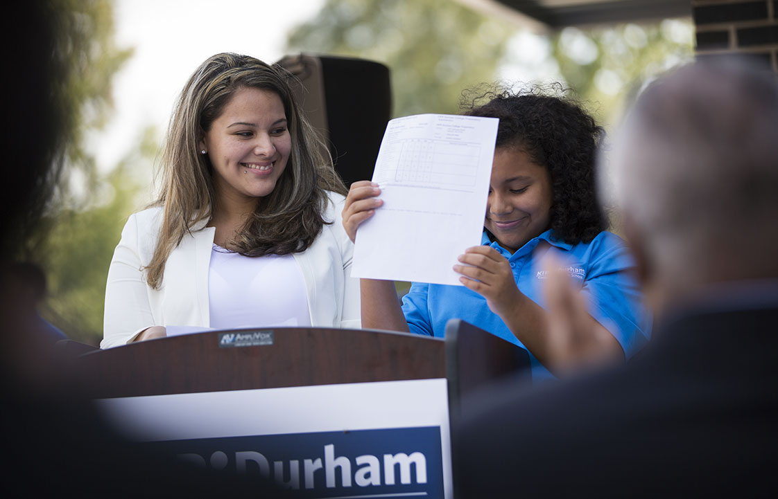 Kayla Meija, age 11, holds up her report card as she speaks to attendees at the KIPP Durham ribbon-cutting ceremony with her mother Cynthia Vargas on Friday, September 16, 2016. Mejia received all A's on her report card last year at the end of 5th grade.