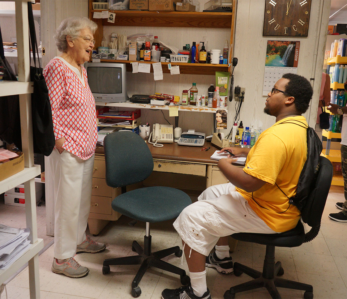 Getting an earful: VOICE reporter Yusuf Shah listens as 83-year-old Julia Hutcherson relates the long history of Ocracoke's iconic Variety Store. (Jock Lauterer photo)