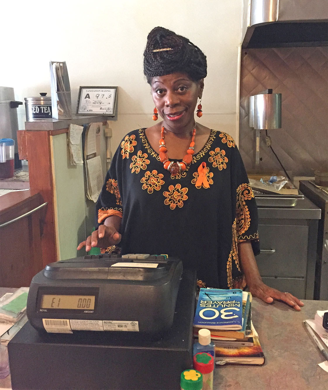 Phyllis Terry, the owner of JC’s Kitchen, works at the checkout desk where a pile of Christian books is placed. (Staff photo by Heng Su) 