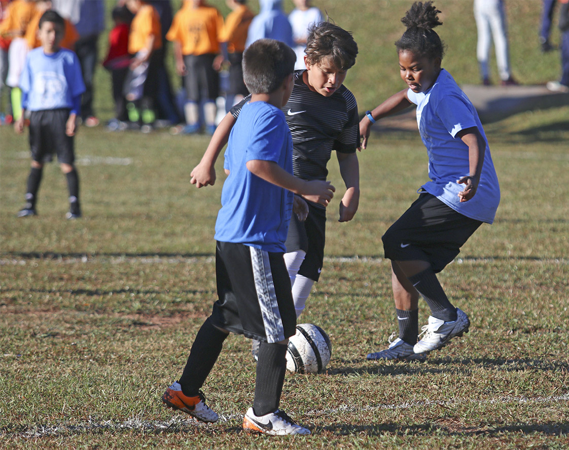 Third grader Kayden Sims helps her teammate on the Eastway Elementary School team as they take on Merrick-Moore Elementary School during the Police Athletic League soccer game on Saturday, Nov. 5. (Staff photo by Brenna Elmore)